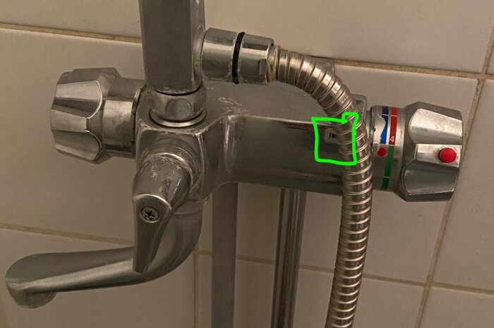 Metallblandare för dusch, temperaturmärkning, sliten, kromad finish, duschslang ansluten, grönt märkt område.