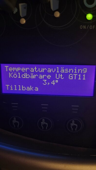 Digital display visar temperaturavläsning, "Köldbärare Ut. GT11 3,4°", med knappar nedanför och blått ljus.