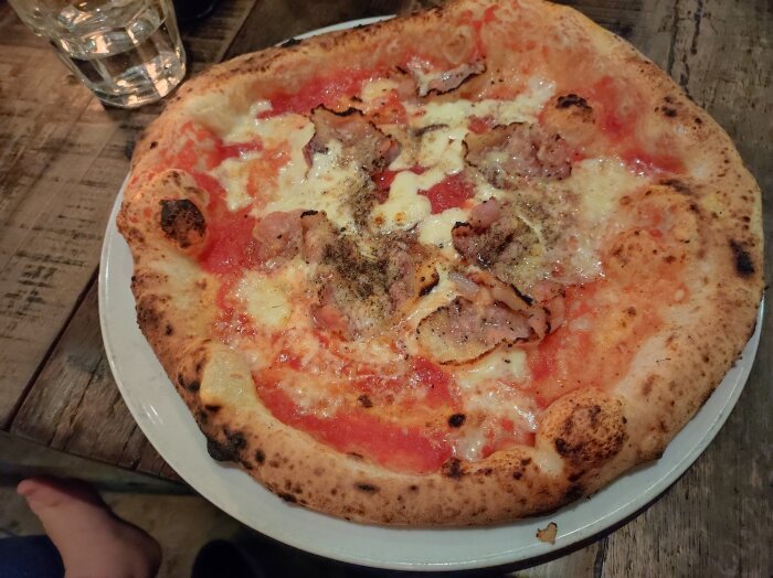 Napolitansk pizza med tomatsås, ost och skinka på träd bord, fotogenik, informell middag.