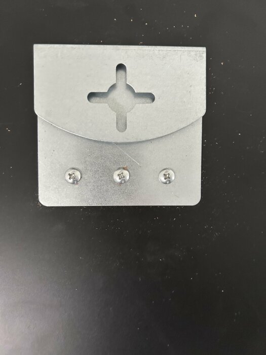 Peilinkiinnike, jossa on kolme ruuvia ja ristinmuotoinen aukko, mustalla taustalla.