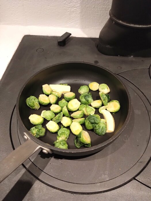 Stekpanna med Brysselkål på spishäll, matlagning, kök, gröna grönsaker, sund mat.