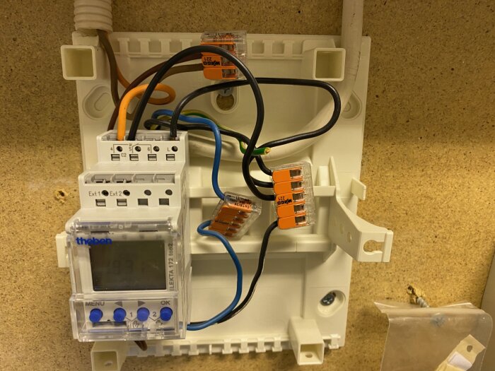 Elektrisk installation med timers, säkringar, och kopplingsklämmor på monteringsskena.