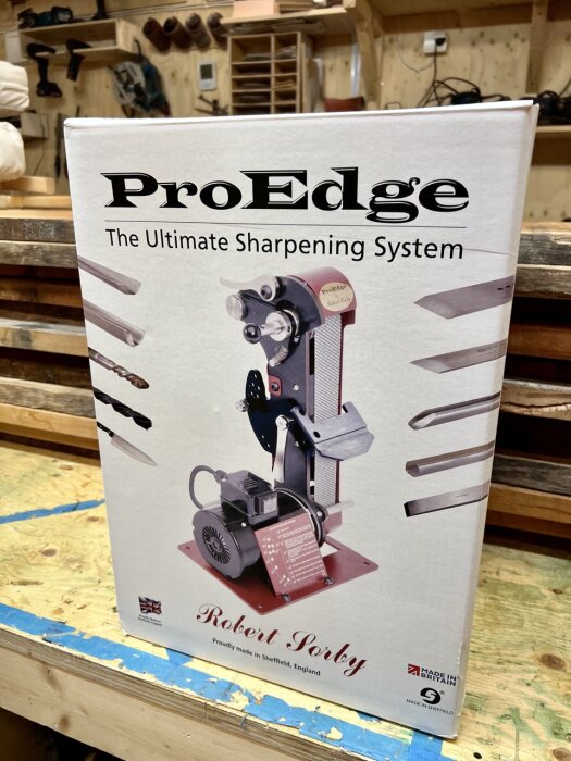 Kartong med ProEdge slipningssystem, Robert Sorby logo, verktygsbilder, "Made in Britain"-märke, snickarverkstad bakgrund.