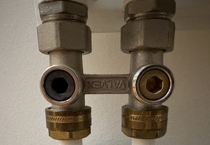 Två metallrörkopplingar med märkningen "VALTEK", ihopkopplade, på en vägg.