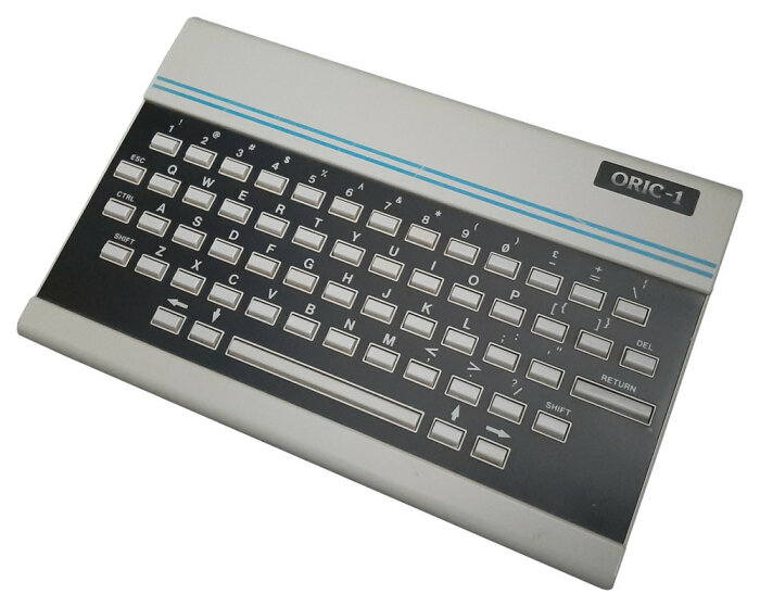 Retro Oric-1 dator, inbyggt tangentbord, tidig hemdator, grå, blå detaljer, vintage teknik.