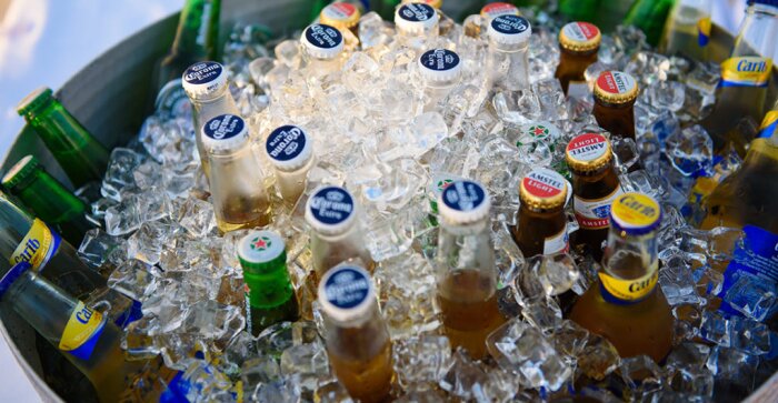 Ölflaskor i varierande märken svalkas i is i en hink.