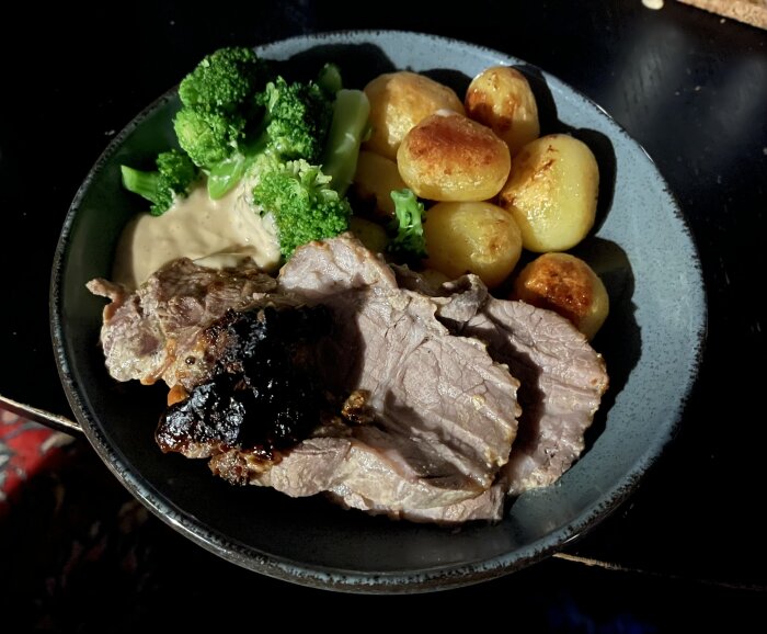 Middagstallrik med stekt kött, potatisar, broccoli och sås. Rik och näringsrik måltid.