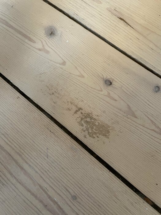 Trägolv med smutsfläckar och märken, diagonala brädor. Neutral färgpalett.