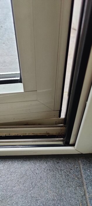 Dörröppning, smutsiga fönsterkenor, vatten på glas, inomhus och utomhus synliga.