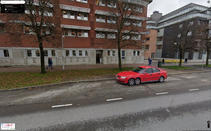 Stadsbild med personer, byggnader, röd bil på gata, molnig dag, gångväg, träd utan löv.