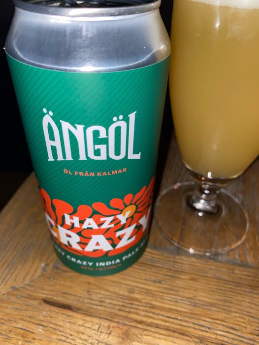 Ölburk märkt "ÄNGÖL" från Kalmar, "Hazy Crazy" India Pale Ale, bredvid ett glas öl.