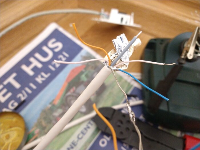 Elektriska ledningar sammanbundna ovanpå en tidning i rörigt skrivbordsscenario.