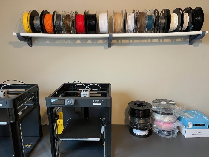 3D-skrivare med filamentrullar på hylla och bord, modern teknik för 3D-utskrift.