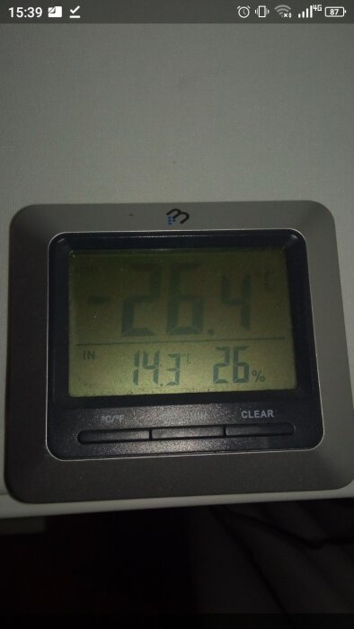 Digital termometer som visar inomhustemperatur och luftfuktighet. Skärmen visar -26.4°C och 26% fuktighet.