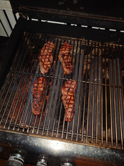 Tre grillade stekar på en gasolgrill. Matlagning, utomhus, middagsförberedelse, grillränder, smaklig måltid.
