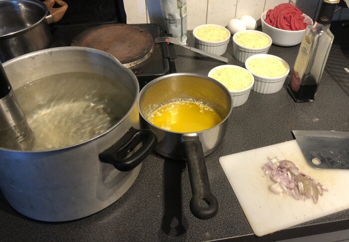 Matlagning på spis, kastruller, sås, ris, ägg, lök, skärbräda, kök, olja.