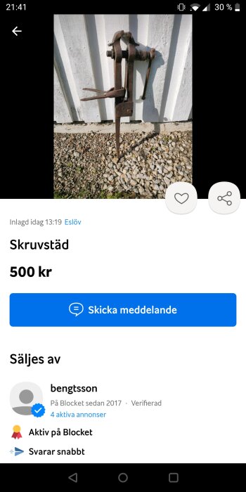 Gamla skruvstäd till salu för 500 kr på Blocket; rostig, placerad mot vit vägg och grus.