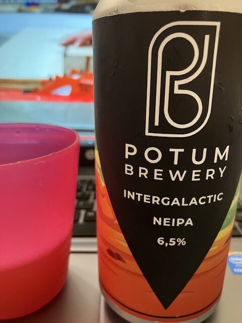 Ölburk från Potum Brewery, "Intergalactic NEIPA", framför dator och röd mugg.