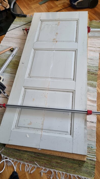 Vit dörr ligger på golvet, verktyg runt omkring. Renovering eller reparation pågår.