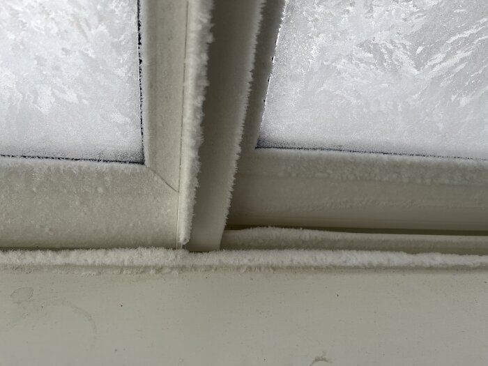 Fönster med iskristaller, frostigt mönster, kallt, vinter, inomhus vy mot tak och karm.