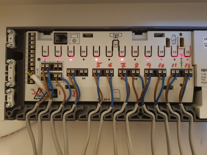 Ett elektriskt styrsystem med kablar, kontakter och lysdioder monterade i en grå låda.