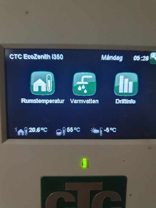 Kontrollpanel för värmesystem, visar rumstemperatur, varmvatten och driftinformation, samt datum och tid.