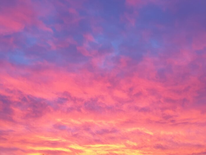 Dramatisk himmel vid solnedgång med rosa och blå nyanser, molnformationer, levande färger, ingen synlig horisont.