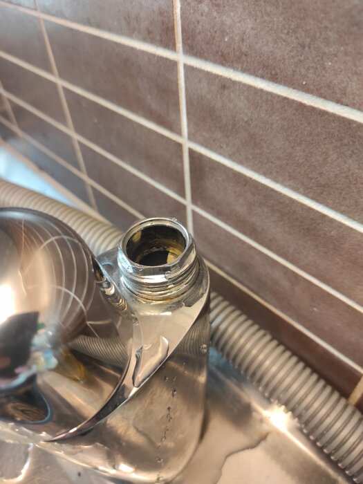 Vattenkokare utan lock i rostfritt stål på en köksbänk med kakelvägg.
