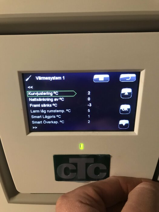 Digital kontrollpanel för värmesystem, finger pekar, inställningsalternativ på skärmen, grönt ljus, CTC-logotyp.
