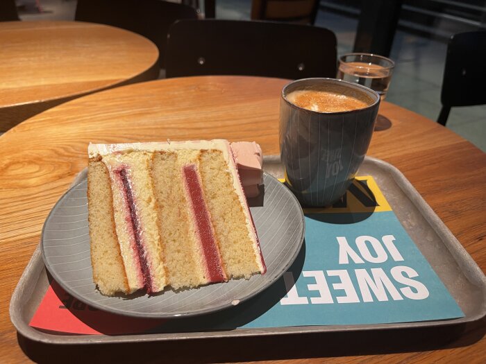 Ett skivat lager-tårta och kaffe på ett fat i en café-miljö.