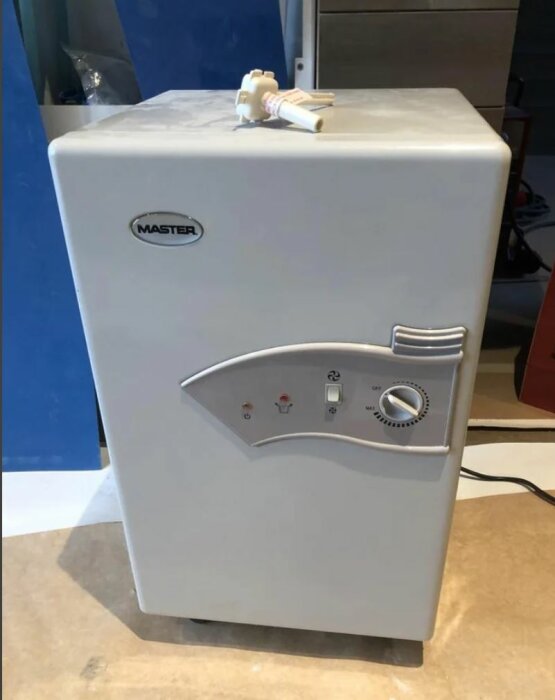 Vit luftavfuktare med inställningsreglage och indikatorlampor på överdel, placerad inomhus mot blå vägg.