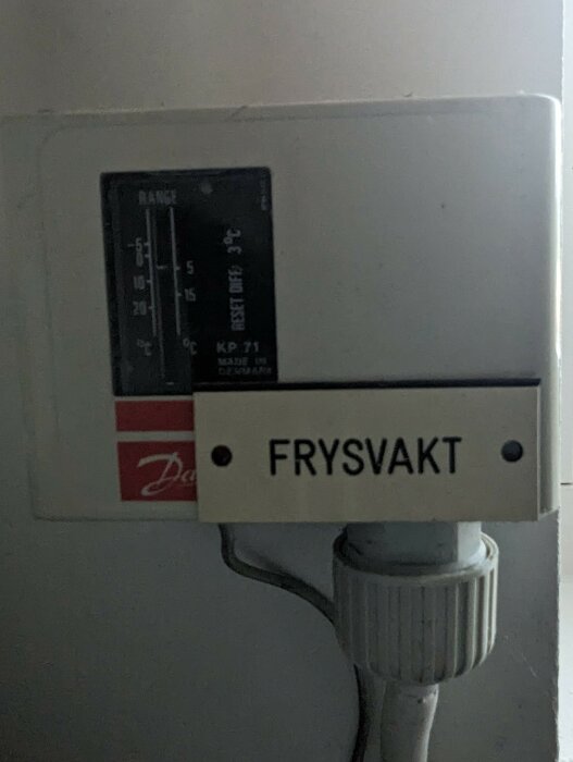 Termostat med skalan -5 till +30 grader Celsius märkt "FRYSVAKT", monterad ovanpå rör.