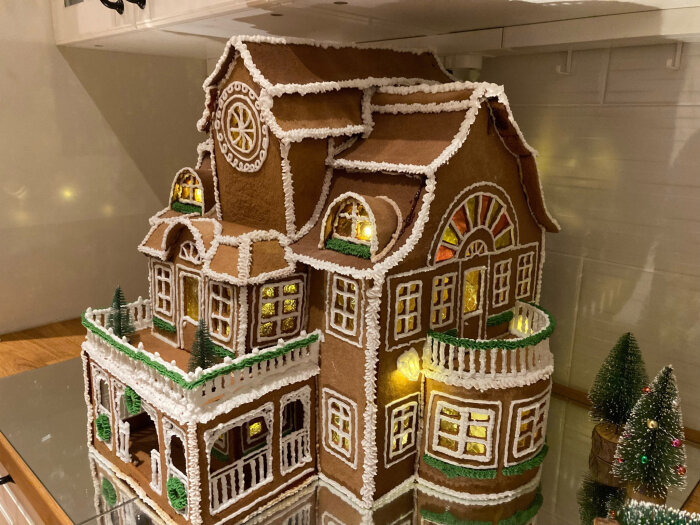 Ett komplex och detaljerat pepparkakshus med dekorativt kristyr och inbyggd belysning, uppställt för julvisning.