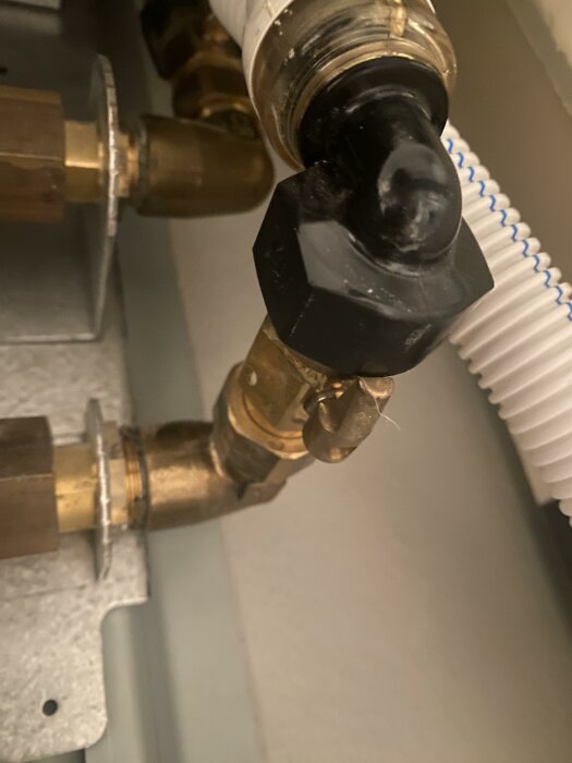 VVS-installation med kopparledningar och ventil, närbild, fokus på svart plastskydd, möjlig skada eller smältning.