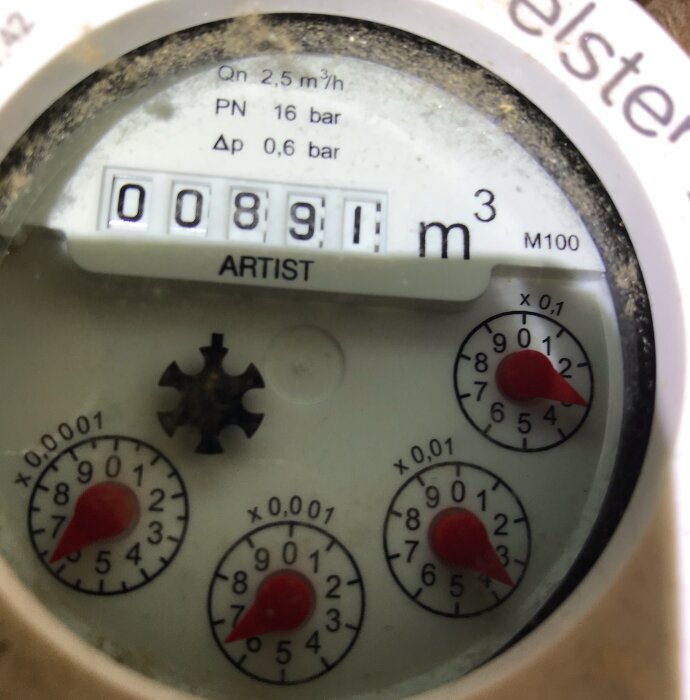Vattenmätare med räknare, tre röda indikatorknappar, dammigt glas och tekniska specifikationer.