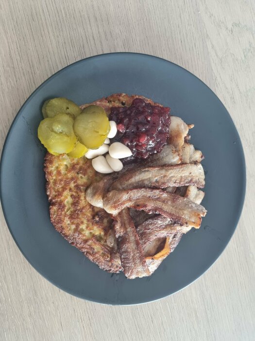 Tallrik med pannkakor, sylt, bacon, inlagda gurkor och vitlöksklyftor.