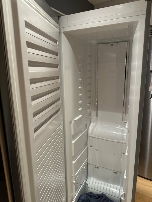 Tom kylskåp öppen, hyllor och lådor, inget innehåll, inomhus, modern design.