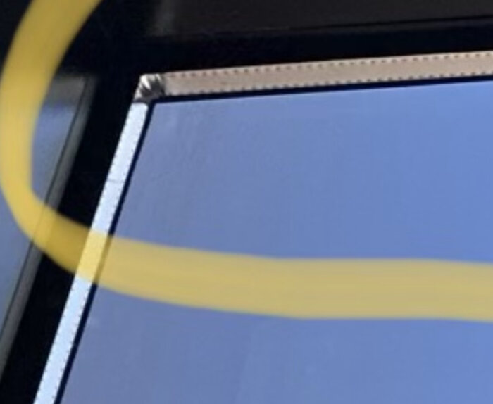 Del av gul ring, blå bakgrund, möjligt fönsterhörn, suddig förgrund.