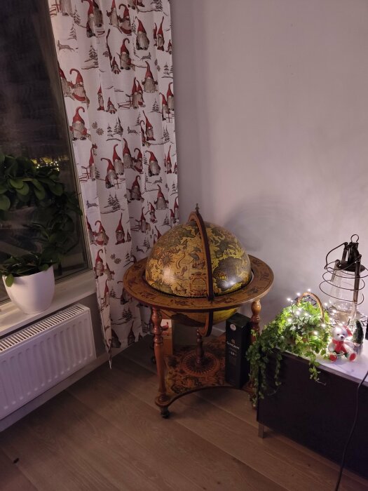 Hörn av ett rum med glob, julgardiner, växter och dekorativ belysning.