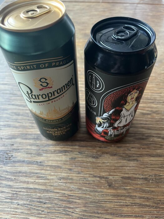 Två ölburkar på ett träbord, en mörk och en ljus.