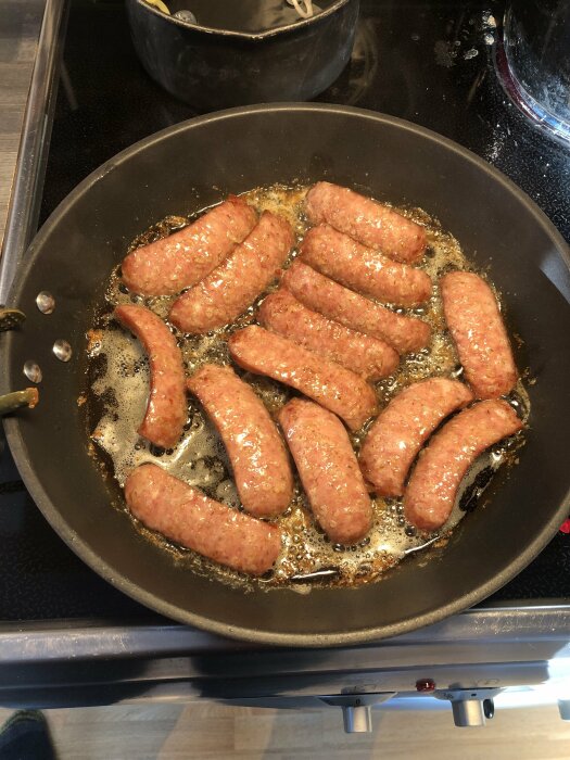Korvar som steks i en panna med bubblande olja på en spis.
