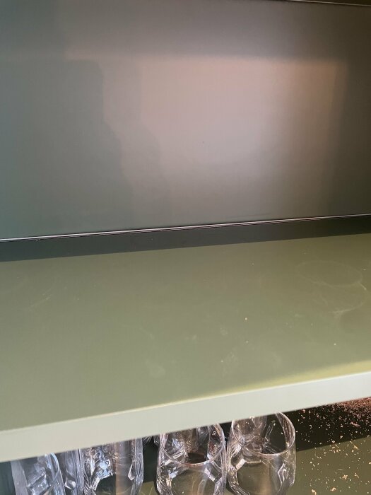 Inomhus, kökshylla, genomskinliga glas, grå bakgrund, grönt bord, minimalistisk design, sparsamt med detaljer.