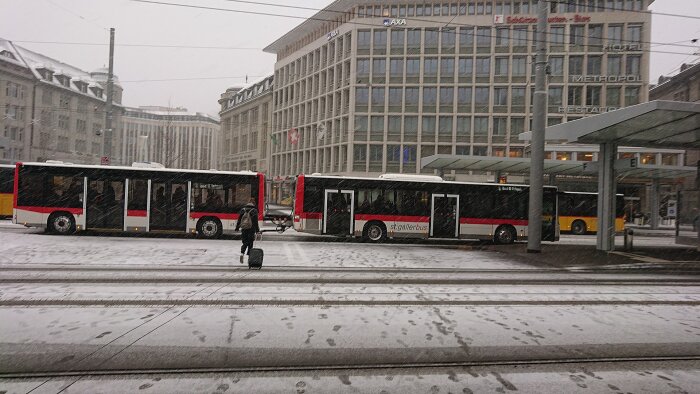 Snöig stadsscen med buss, övergångsställe och en ensam person.