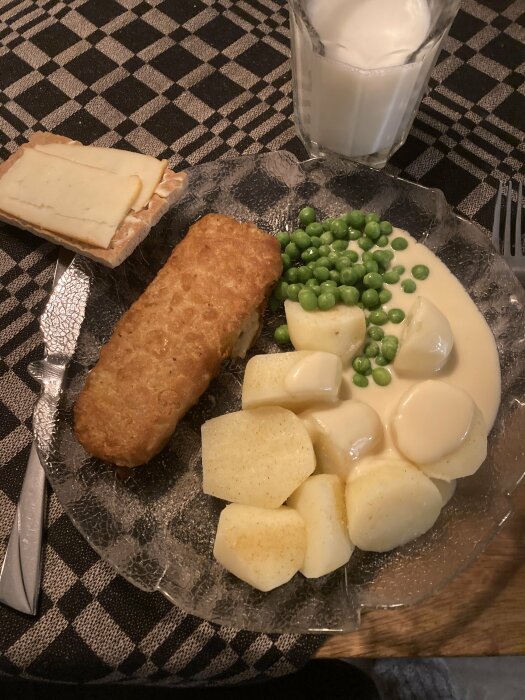 Husmanskost: köttbulle, potatis, ärter, sås, smörgås med ost, mjölkglas, rutig duk.