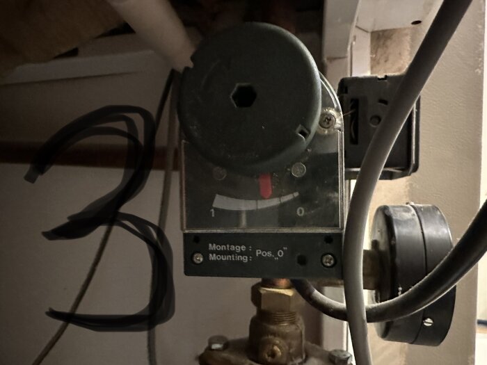 En industrikontrollpanel med knappar och kablar, skymd av suddig, svart scribble på bilden.