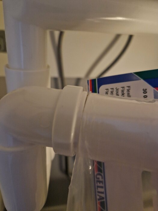 Närbild på vit plastflaska och rör, möjligtvis en del av en medicinsk apparat eller maskin.