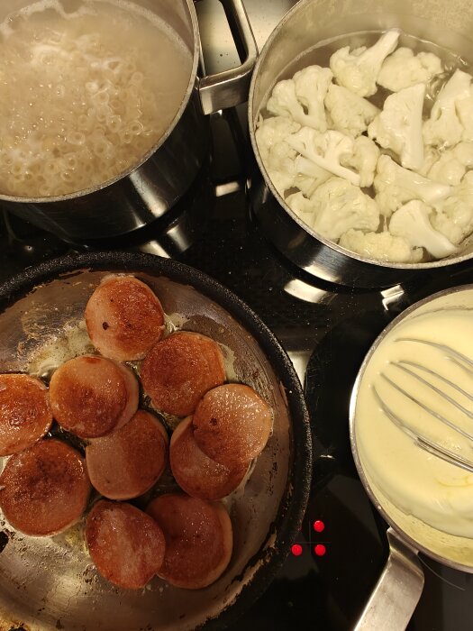 Matlagning på spisen: pasta kokar över, stekt korv, blomkål ångas, sås vispas i kastrull.