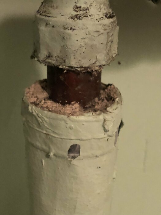 Rörledning med isolering och skador, rost och avlagringar synliga, behov av underhåll eller byte.