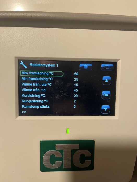 Display för värmesystem visar temperaturinställningar och status, omgiven av grå plast och CTC-logotyp.