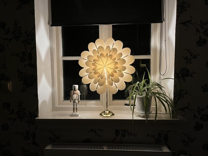 Mysigt fönster, ljusstake, blomstrande lampa, grön växt, nutcracker, blommigt tapet, natt.